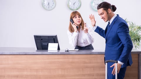 an unhappy hotel guest in front of the check-in desk