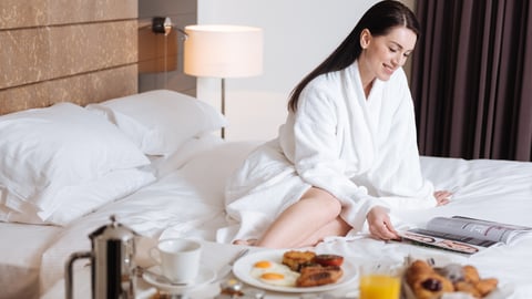 a woman sitting on a hotel bed with room service