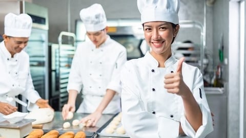 a group of people standing in a kitchen preparing food