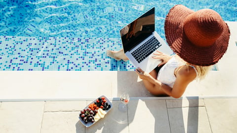 woman using laptop by the pool