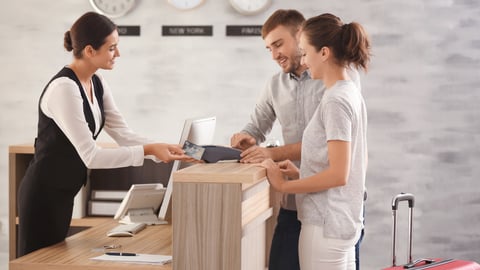 travelers paying at front desk in hotel lobby