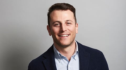 a man wearing a suit and tie smiling at the camera