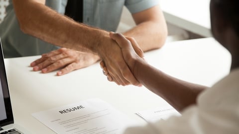 two people shaking hands, piece of paper that reads resume