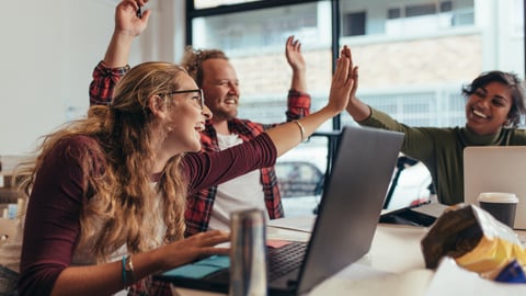 people in an office high-fiving and cheering