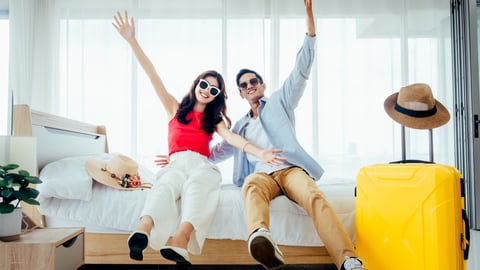 two people falling happily onto a hotel bed