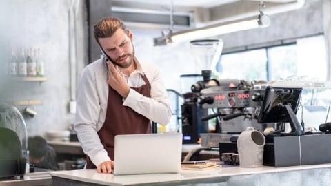 coffee shop owner looking at bottomline on pc