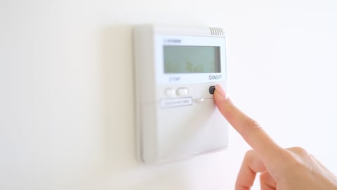 person touching the thermostat in a hotel room