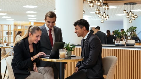 young adults in a hotel lobby looking at a laptop computer