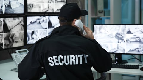 Male security guard talking by telephone in surveillance room; Shutterstock ID 1008332989