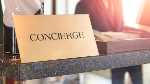 Concierge service desk counter with happy employee staff receptionist working in front of hotel with tourist guest business customer.; Shutterstock ID 1246604926