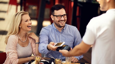 Happy couple having fun while making contactless payment via smart phone in a bar. ; Shutterstock ID 1465891616