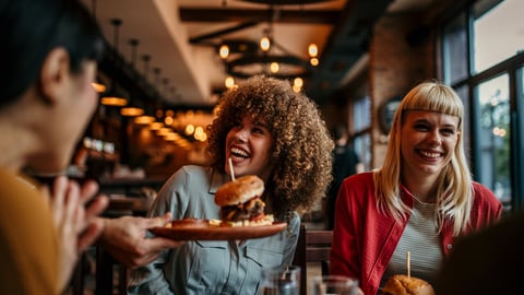 Waiter serving food to a group of customers at a restaurant; Shutterstock ID 2480557461