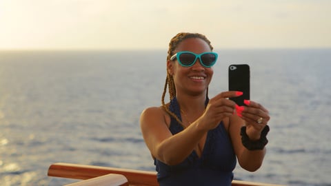woman using internet on smartphone while on cruise, in ocean