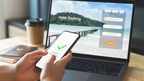 Hand using laptop and booking hotel on website for vacation after a long work and payment completed message on mobile, Summer holiday concept.; Shutterstock ID 2375160831