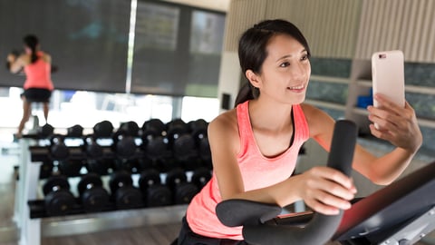 Woman biking at gym and taking selfie; Shutterstock ID 602904494