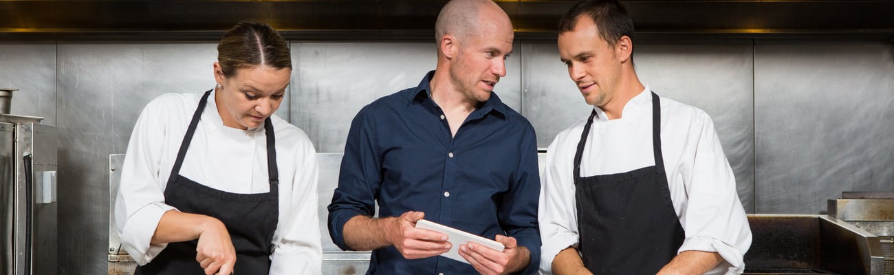 a group of people standing in a kitchen preparing food