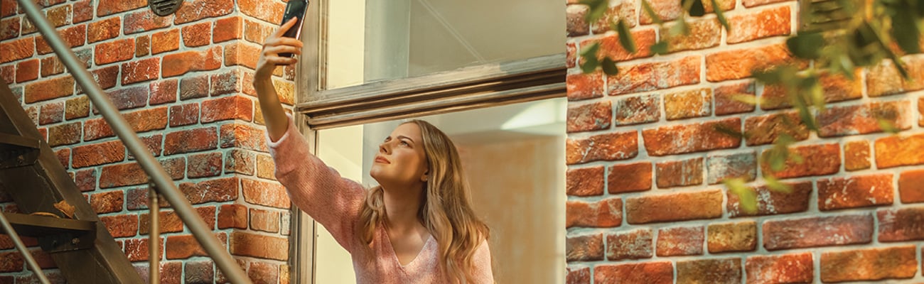 woman leaning out window looking for cellular signal