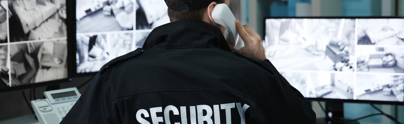 Male security guard talking by telephone in surveillance room; Shutterstock ID 1008332989