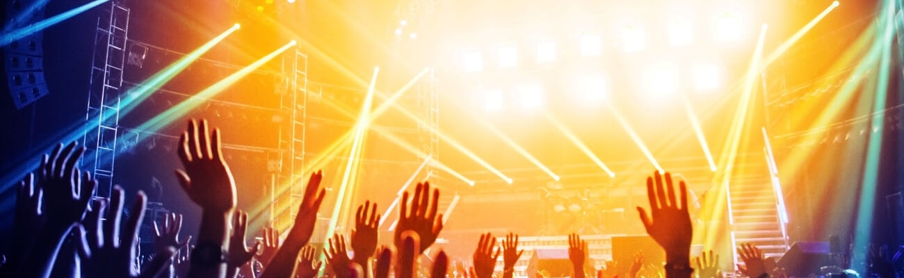 Photo of young people having fun at rock concert, active lifestyle, fans applauding to famous music band, nightlife, DJ on the stage in the club, crowd dancing on dance-floor, night performance; Shutterstock ID 129152783