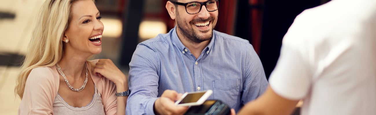 Happy couple having fun while making contactless payment via smart phone in a bar. ; Shutterstock ID 1465891616