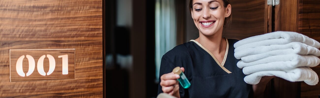 Beautiful young hotel chambermaid in uniform bringing clean towels and other supplies to hotel room.; Shutterstock ID 2127387344