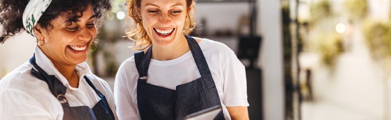 Happy female employees using a mobile app on a tablet to manage the daily operations of their restaurant. Women working together to ensure that customers receive the best hospitality service.; Shutterstock ID 2363837863