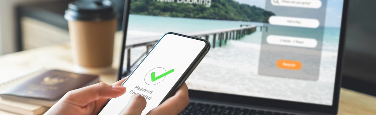 Hand using laptop and booking hotel on website for vacation after a long work and payment completed message on mobile, Summer holiday concept.; Shutterstock ID 2375160831