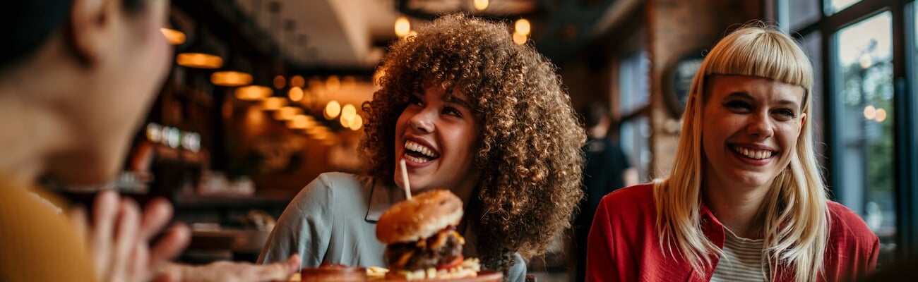 Waiter serving food to a group of customers at a restaurant; Shutterstock ID 2480557461