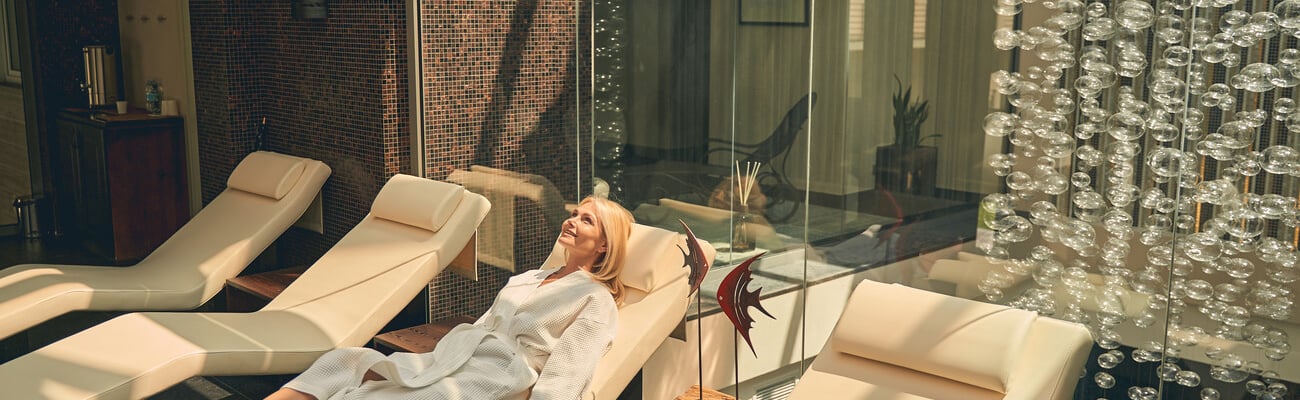 Top view of charming female wearing white bathrobe while lying on the sun bed in spa resort hotel; Shutterstock ID 1788966920