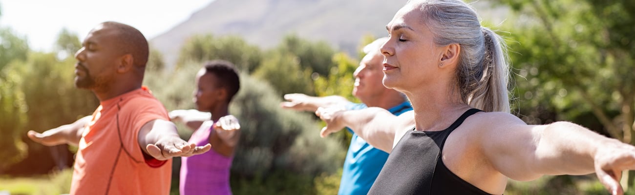 Group of senior people with closed eyes stretching arms outdoor. Mature yoga class doing breathing exercise. Women and men doing breath exercise with outstretched arms. Balance and meditation concept.; Shutterstock ID 1418121728