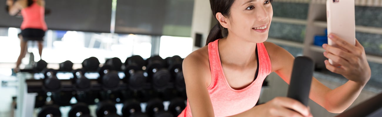 Woman biking at gym and taking selfie; Shutterstock ID 602904494