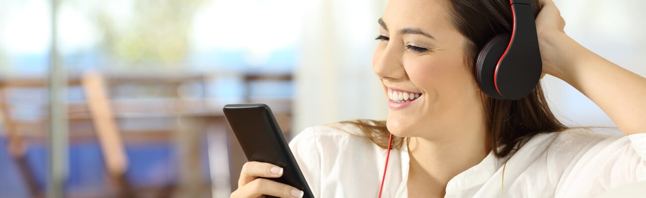 Happy girl listening to music in a beach apartment sitting on a sofa in the living room; Shutterstock ID 758208631