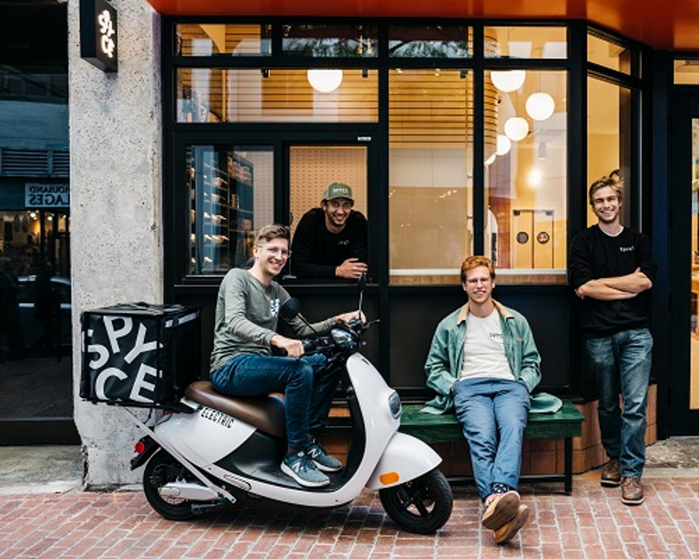 a group of people sitting on a motorcycle in front of a building