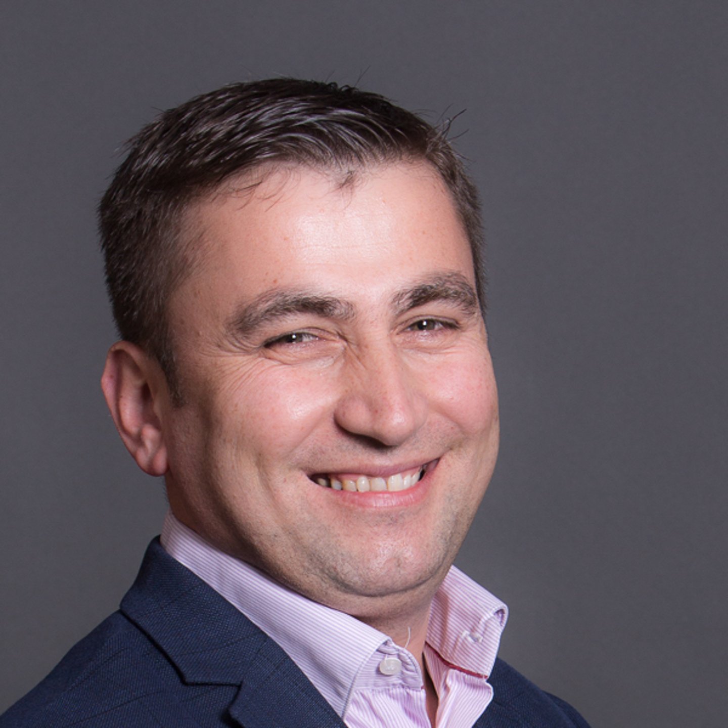 a man wearing a suit and tie smiling at the camera