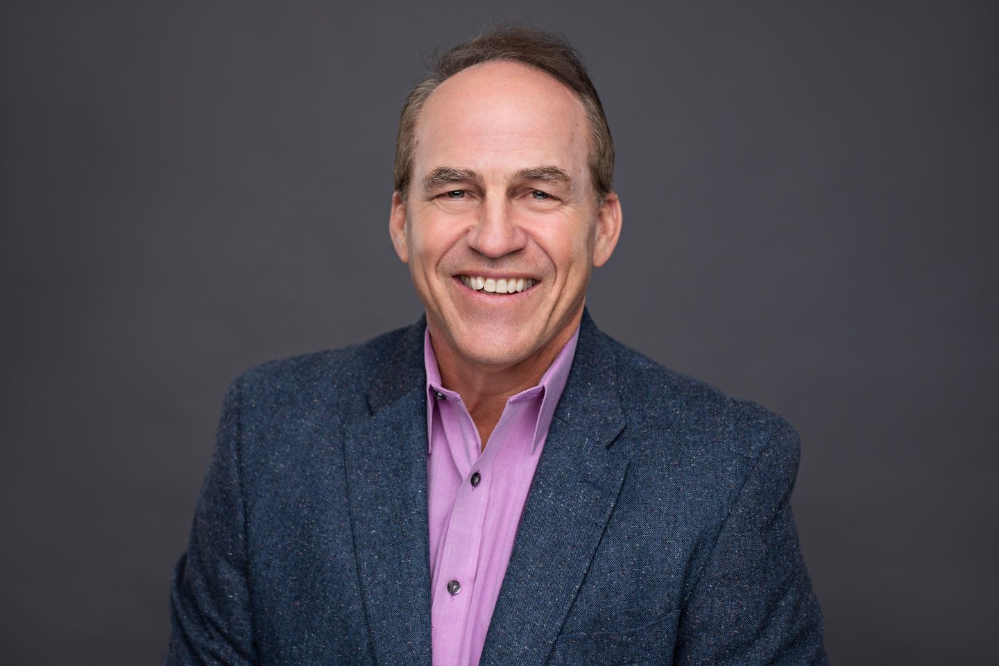 a man wearing a suit and tie smiling at the camera