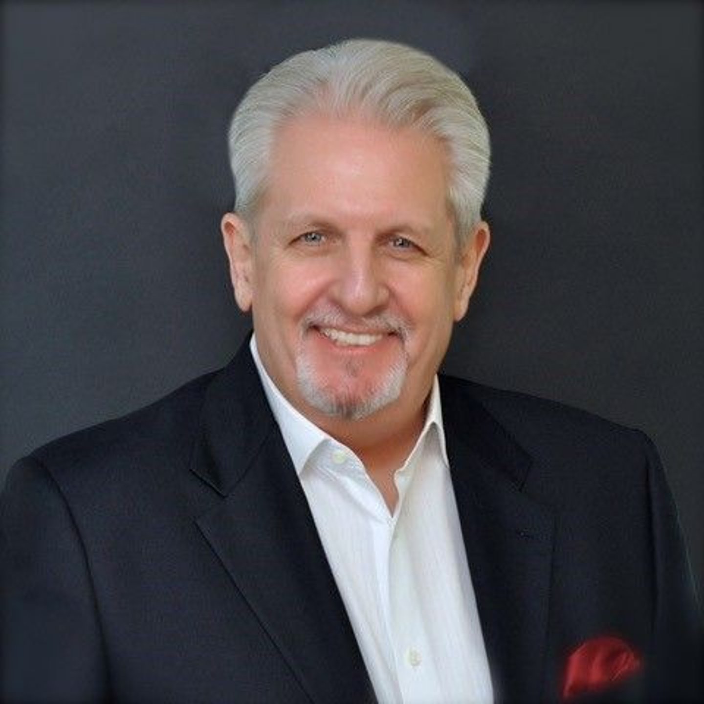 a man wearing a suit and tie smiling at the camera