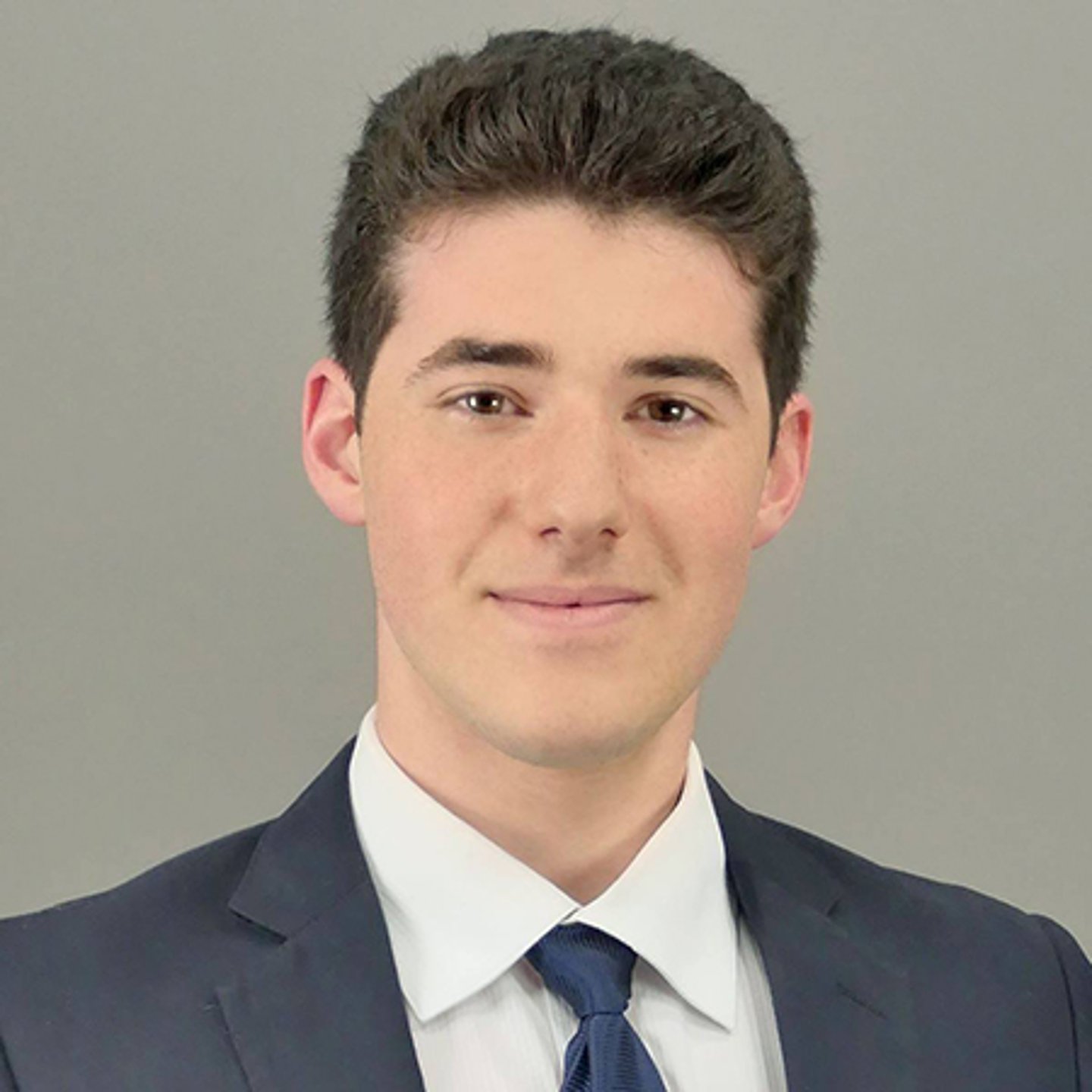 a man wearing a suit and tie smiling at the camera