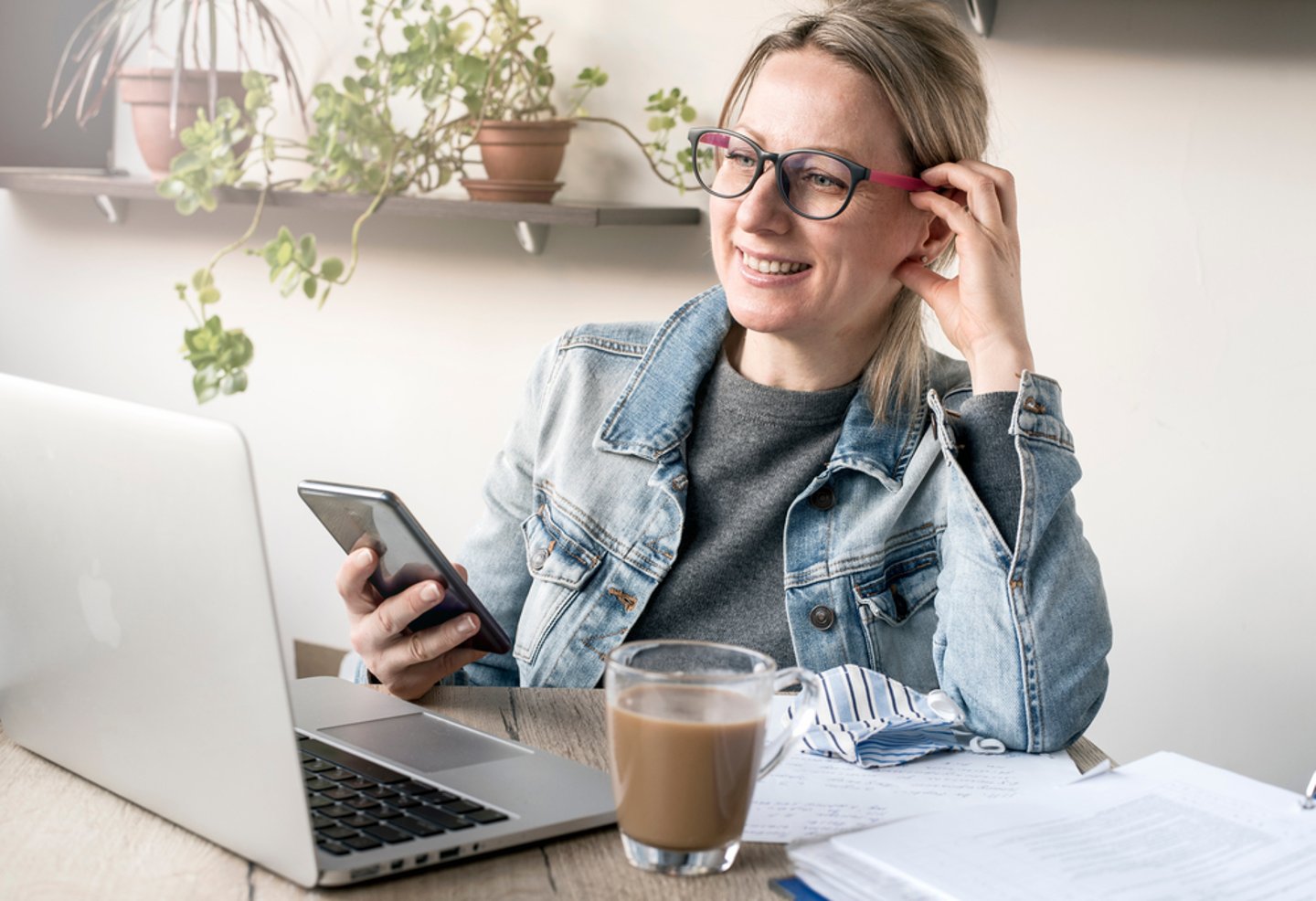 a person sitting at a table using a laptop while talking on the phone