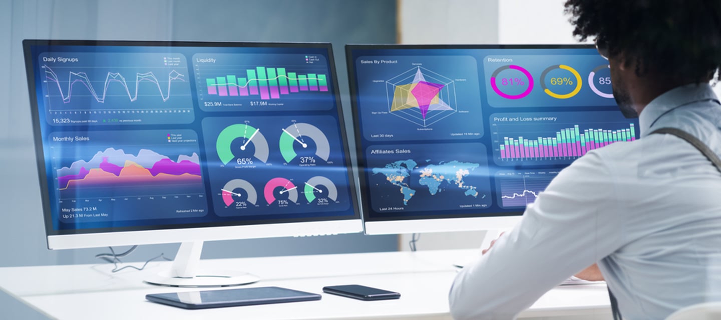 Man in front of computer screens using predictive analytics software