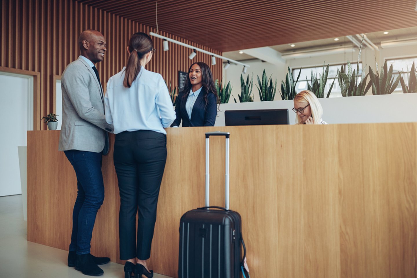 a couple with their suitcase at a hotel front desk