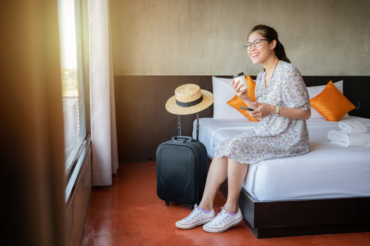 woman sitting on hotel bed, smiling