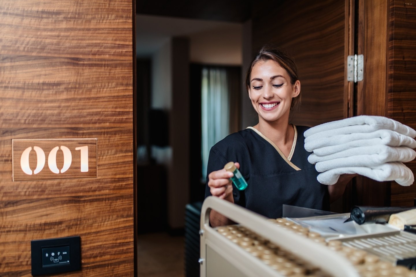 a housekeeper brining towels into a hotel room