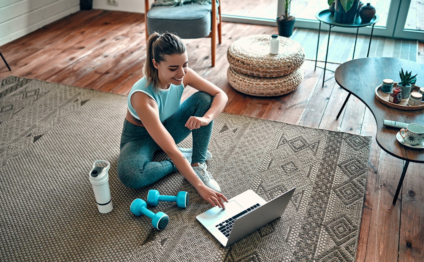 woman getting ready to exercise while watching her laptop