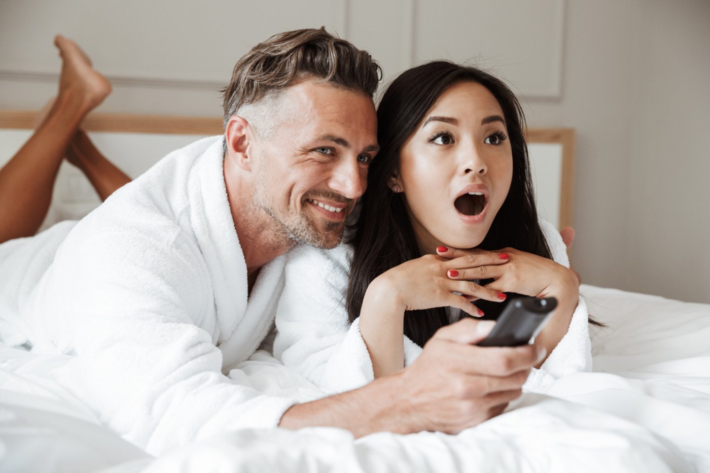 man and woman watching tv in bed