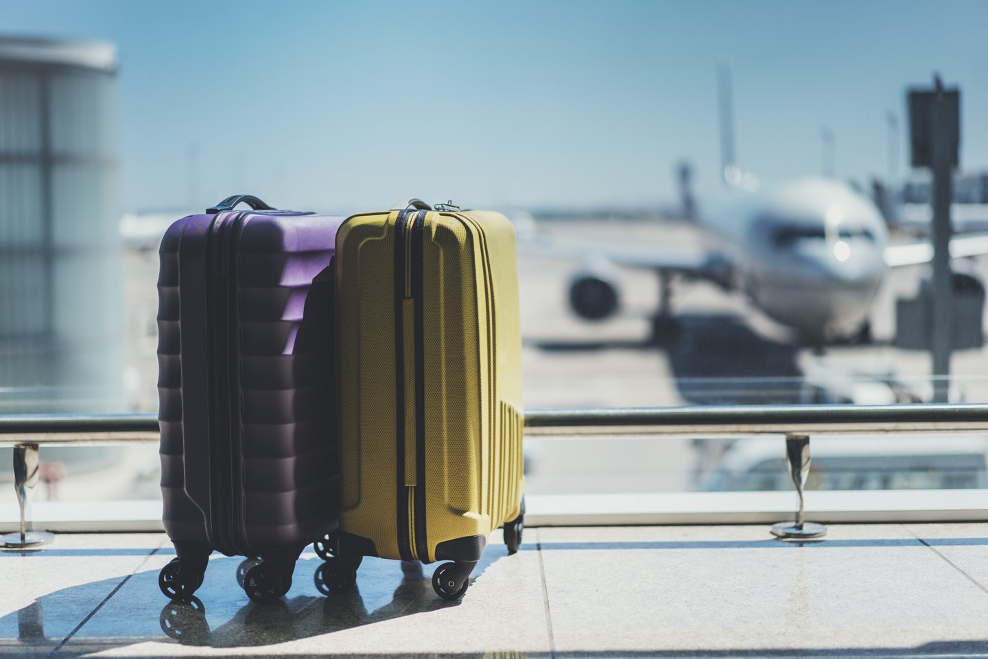 two suitcases with an airplane in front of them at the airport