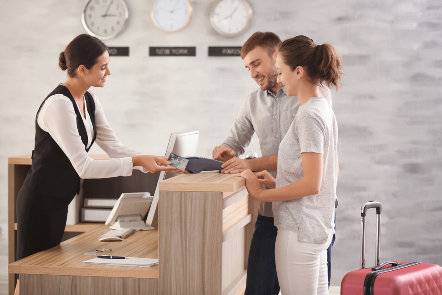 travelers paying at front desk in hotel lobby