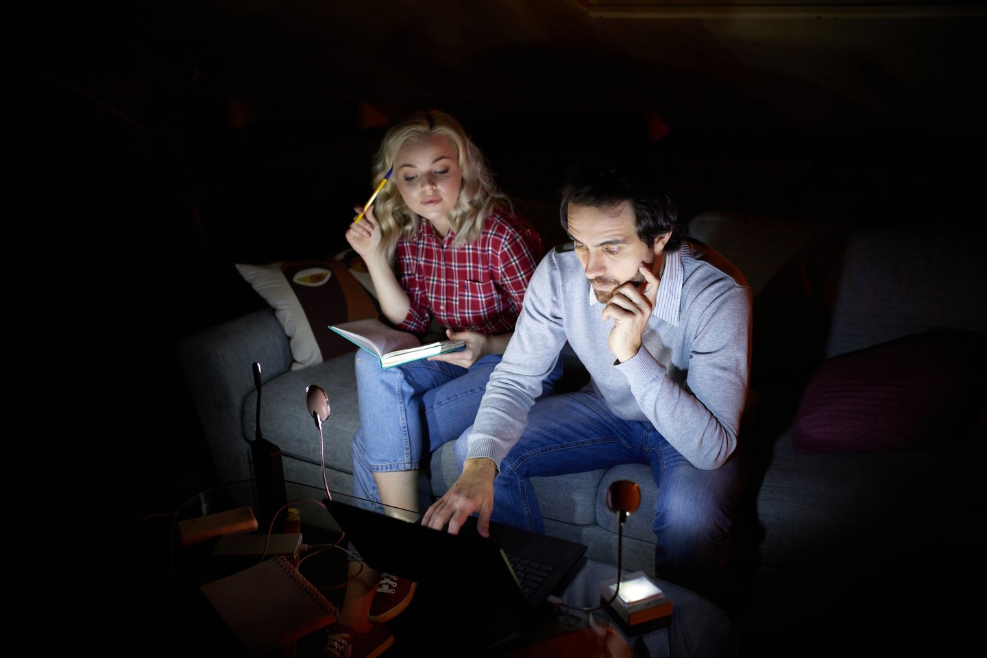 man and woman looking at laptop in the dark during power outage