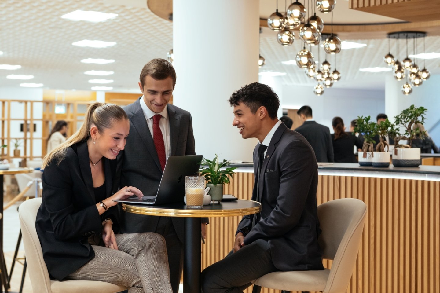 young adults in a hotel lobby looking at a laptop computer