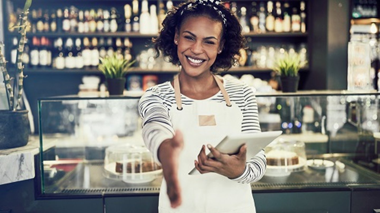 woman in restaurant smiling holding a tablet 