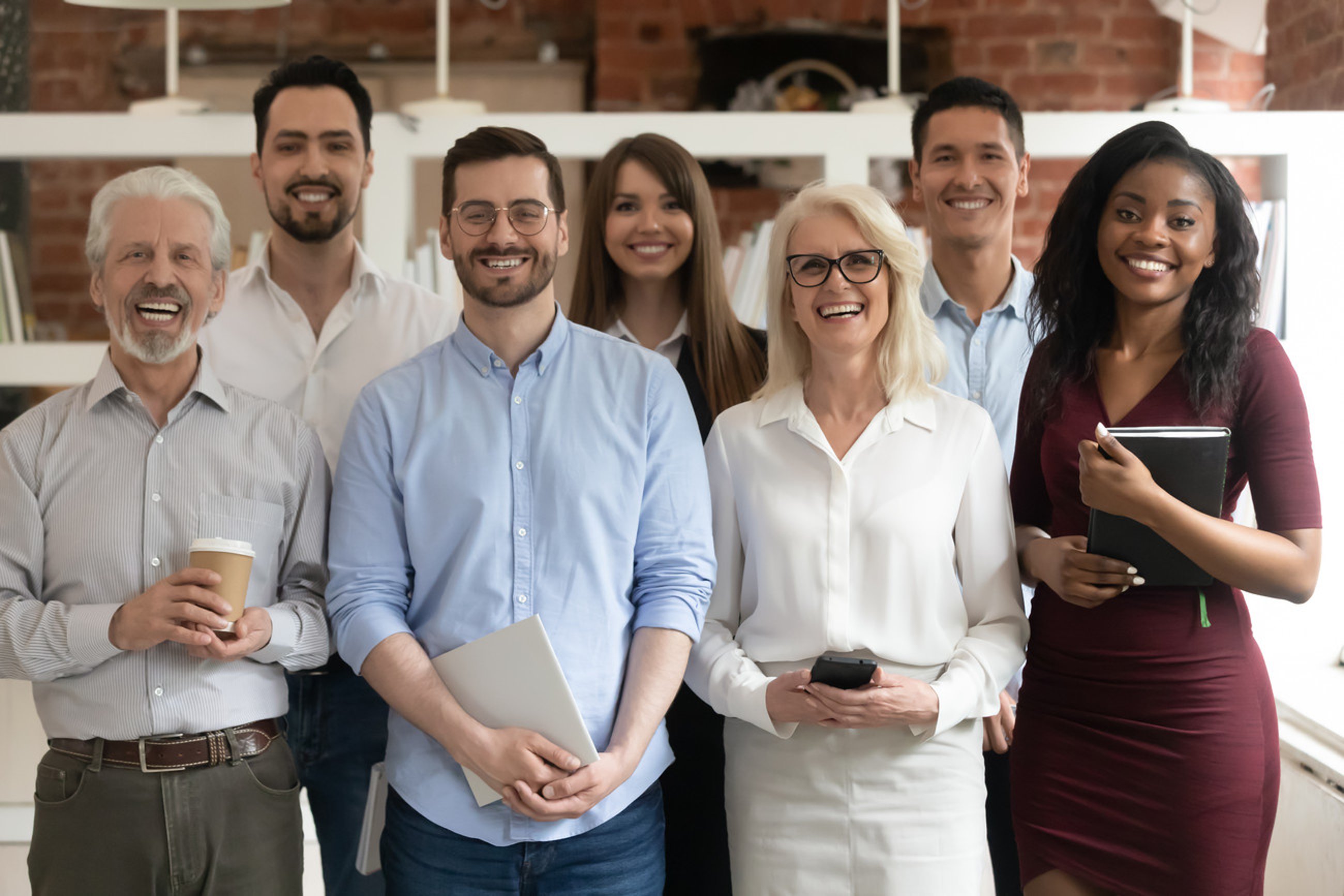 Happy diverse professional business team stand in office looking at camera, smiling young and old multiracial workers staff group pose together as human resource, corporate equality concept, portrait; Shutterstock ID 1437231731